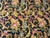 Close-up of hand-stitched acanthus leaves, pink tulips and blue grape clusters on black wool