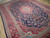 Close angle on red main border, guard stripes and navy floral field of hand-knotted wool rug