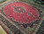 Angled view showing raspberry red field, ivory guard borders and glossy hand-knotted wool pile