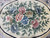 Macro view of hand-carved pink, blue and olive flowers inside the ivory oval medallion