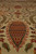 Macro view of rust and burgundy lattice-filled boteh outlined in olive on ivory wool