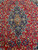 Close-up of navy blue medallion with terracotta cartouche centre and blue green flowerheads on red