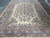 Persian Kerman 9'7" x 14'4" room-size rug seen from the end, ivory field framed by blue border