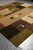 Angled full view of the 12' x 12' modern rug showing brown, olive and beige blocks
