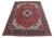 Angled view of red Tabriz wool rug showing ivory corner spandrels and dense floral field