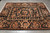 Black ground floral rug photographed at an angle on grey tile, showing inner panel and cornucopia corners