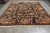 Coral and sage green blossoms covering the black field of this large hand-knotted room size rug
