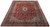 9'10" x 13'2" signed Kashan rug seen at an angle, navy border framing a dense floral field