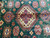 Ivory octagonal center medallion framed by orange and navy hooked diamonds on forest green wool field