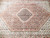 Close-up of hexagonal navy medallion surrounded by rose Herati fish pattern in fine wool
