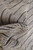 Texture close-up of natural undyed wool pile with irregular black stripe lines across surface