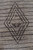 Close-up of the single charcoal diamond motif woven into the light brown wool field