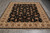 Full view of the black and beige 8x10 Oriental area rug on grey tile