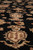 Angled pile close-up revealing dense hand-knotted wool depth and a cream shield cartouche on black