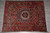 Full overhead view of red and navy tribal Bakhtiar wool rug on grey tile floor