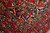 Navy corner spandrel with ivory scrolling vine meeting the burgundy main border of the rug