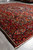 Bakhtiar wool rug photographed at an angle with cotton fringe and wide burgundy floral border