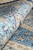 Rolled edge revealing light blue border, ivory guard stripe and lustrous silk pile sheen