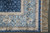 Corner detail with pale blue floral border, navy scroll band and clean ivory silk fringe