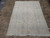 Neutral cream Persian rug in 7x10 size laid flat on stone tile flooring indoors