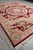 9x12 burgundy Savonnerie area rug displayed at an angle with ivory fringe on grey tile