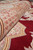 Rolled edge showing plush wool pile depth, dense weave and burgundy field beside the border