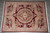 Overhead view of the burgundy French Savonnerie wool rug on grey tile, full medallion visible