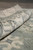 Rolled edge showing low clipped wool depth, ivory border and grayish blue field of the rug