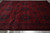 Angled floor view showing dense all-over gul pattern in wine red and black wool