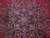 Close-up of navy and ivory 8 petal rosette medallion on deep raspberry red wool field