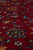 Macro shot of soft wool pile showing blue and gold flowerheads on rich red ground
