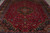 Close overhead angle of red field covered with palmettes, vines and rosettes around navy medallion