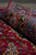 Rolled edge of the wool rug showing navy border depth, blue stripe and red field