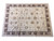 Hand-knotted Peshawar area rug photographed at an angle showing full transitional floral design and brown border