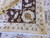 Border corner close-up with gold rosette, ivory leaves, brown ground and clean white cotton fringe