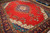 Open red field and navy floral medallion viewed at an angle across the rug