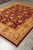 Diagonal perspective showing deep burgundy field, antique gold border and dense wool pile of this rug