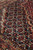 Macro weave detail showing dark navy corner spandrel filled with Herati palmettes and rosettes