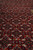 Red field close-up with knotted diamond lattice, small blossoms and fine wool silk sheen