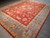 Angled floor view showing the soft blue border and ivory guard stripes framing the coral red field