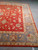 Corner of the rug showing the slate blue border, gold guard band and coral floral field