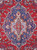 Close-up of sky blue medallion with pink roses and ivory center on red Tabriz field