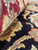 Rolled edge close-up showing burgundy and sage wool against the black floral field beneath