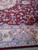 Close view of burgundy field meeting gold border with blue palmettes and leaf scrollwork