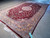 Side angle of the whole rug showing burgundy field, cream medallion and wide border