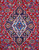 Close-up of the navy and ivory lobed medallion set against a deep red floral field