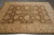 7'7" x 9'8" Ziegler rug photographed flat on grey tile showing beige border and brown field