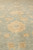 Angled pile view highlighting hand-knotted wool texture and warm gold blossoms against the teal background