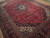 10' x 14' Kashan rug angled view showing deep red field, navy border and ivory spandrel