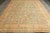 Pastel green and gold Khotan style area rug photographed on grey plank showroom flooring